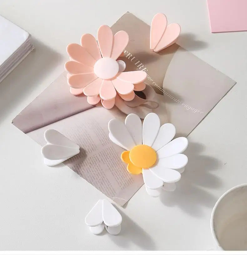 Clips magnéticos de margarita rosa y blanca dispuestos sobre una superficie clara con papel kraft.