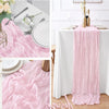 A rustic pink semi-sheer gauze table runner draped on a white tablecloth, shown in detail and in use.