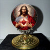 A framed image of Jesus Christ with a halo and a heart, set in a golden tabletop ornament.
