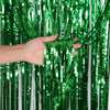 A hand is holding bright green and silver tinsel streamers for birthday decor.