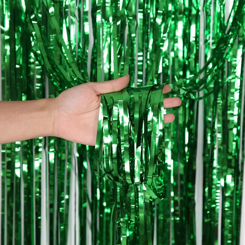 A hand is holding bright green and silver tinsel streamers for birthday decor.