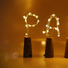 A row of ten glowing LED wine bottle cork lights set against a warm, blurred background.