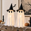 Dos figuras fantasma blancas con sombreros de bruja y ojos brillantes, exhibidas en una superficie de madera para decoración 
