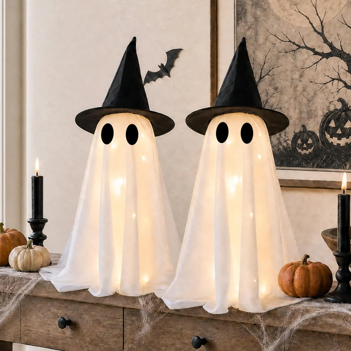 Dos figuras fantasma blancas con sombreros de bruja y ojos brillantes, exhibidas en una superficie de madera para decoración 