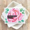 A pink watercolor rose design on a white square stencil and stamp set for DIY scrapbooking