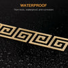 A set of 20 gold-colored acrylic mirror wall stickers featuring a Greek key pattern, shown on a dark, wet surface.