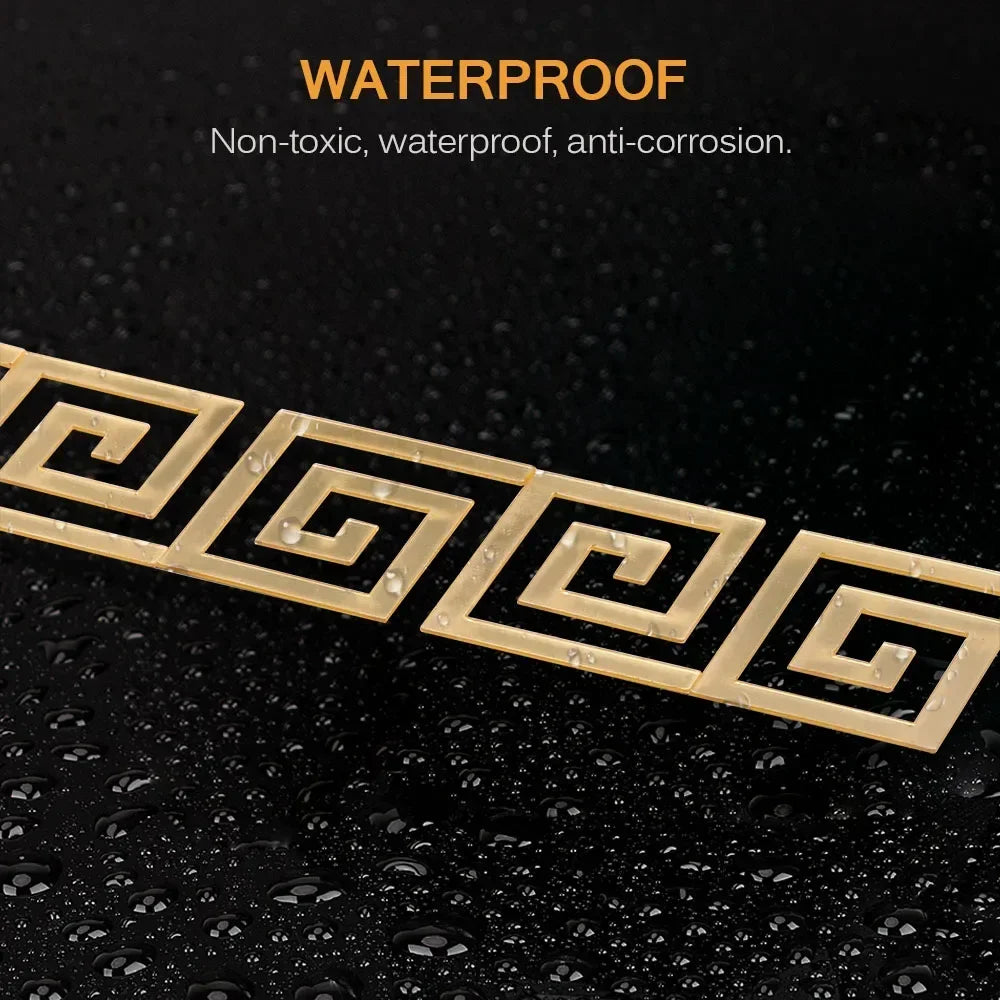 A set of 20 gold-colored acrylic mirror wall stickers featuring a Greek key pattern, shown on a dark, wet surface.