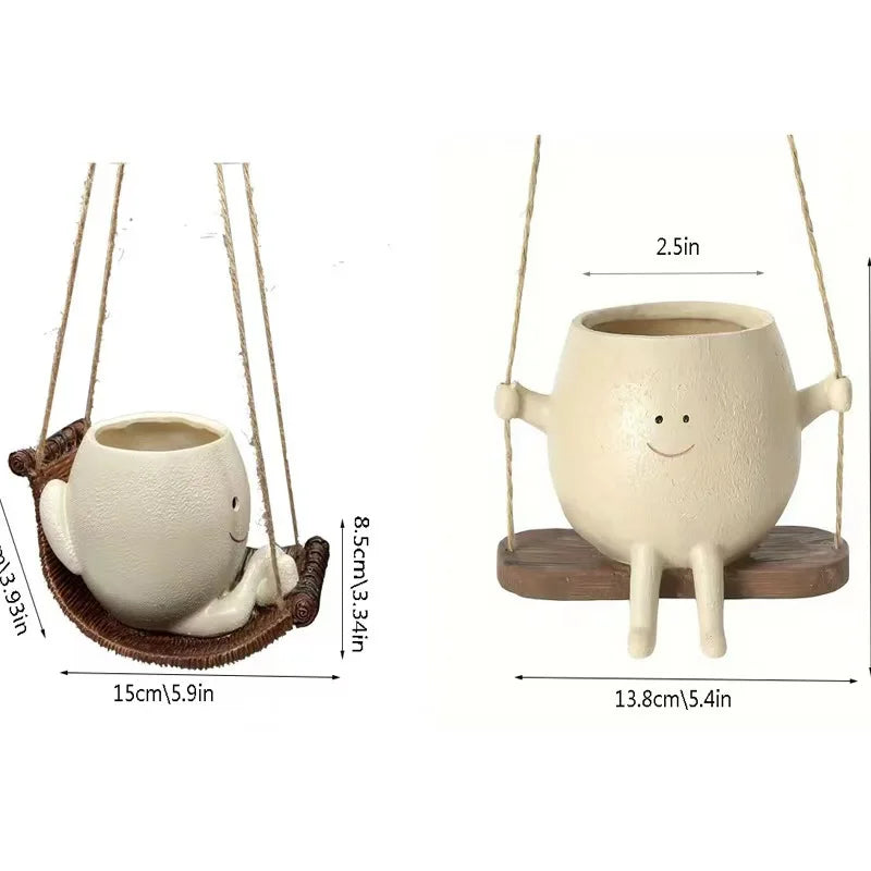 A beige ceramic mug ornament shaped like a smiling face, hanging from a string on a wooden base.