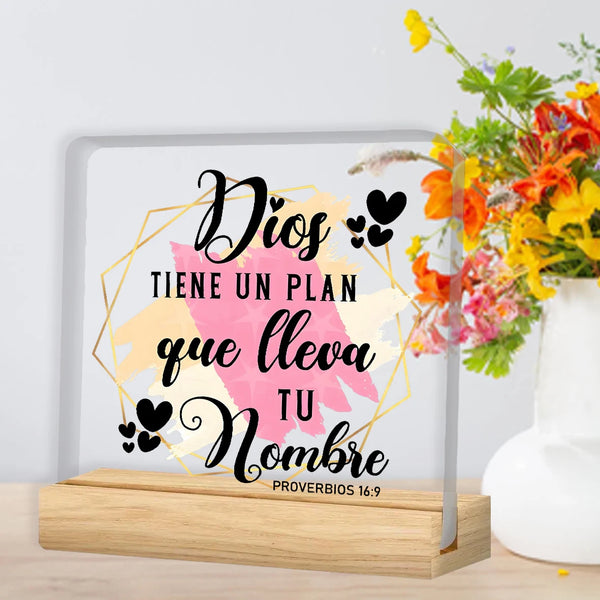 A framed print featuring the text Dios tiene un plan que lleva tu nombre in black script on a light background