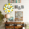 A wooden lemon and leaf wall clock with a silent quartz design hanging on a white wall.