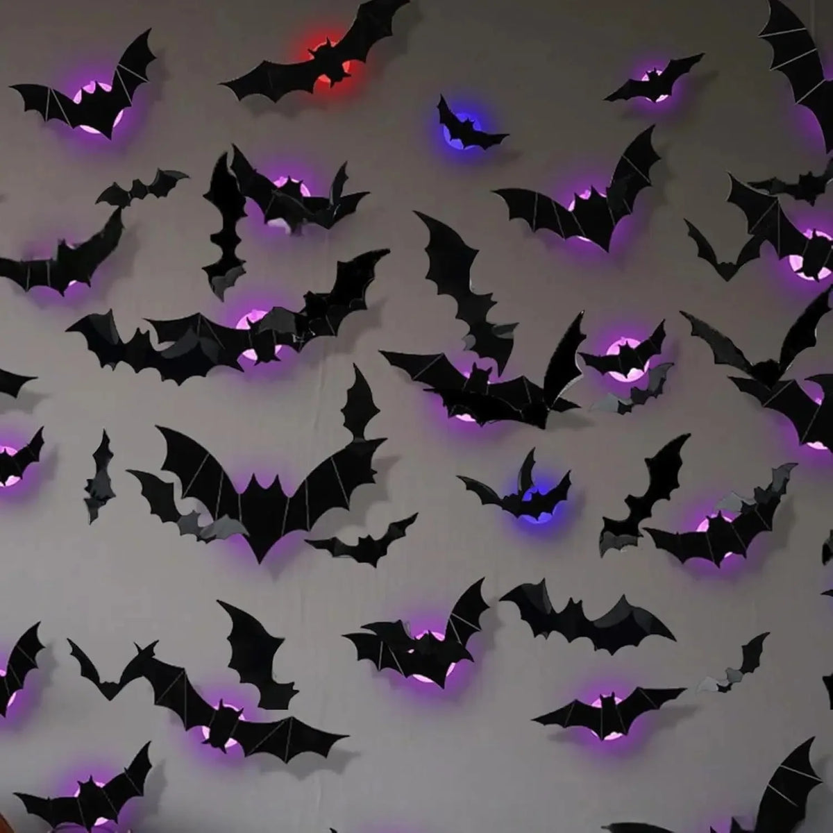 A wall covered in black bat decals illuminated by colorful LED lights.