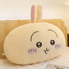 A soft, pale yellow Usagi Chiikawa plush doll with pink ears resting on a white fluffy surface.