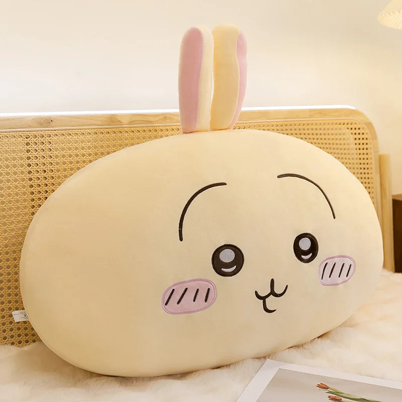 A soft, pale yellow Usagi Chiikawa plush doll with pink ears resting on a white fluffy surface.