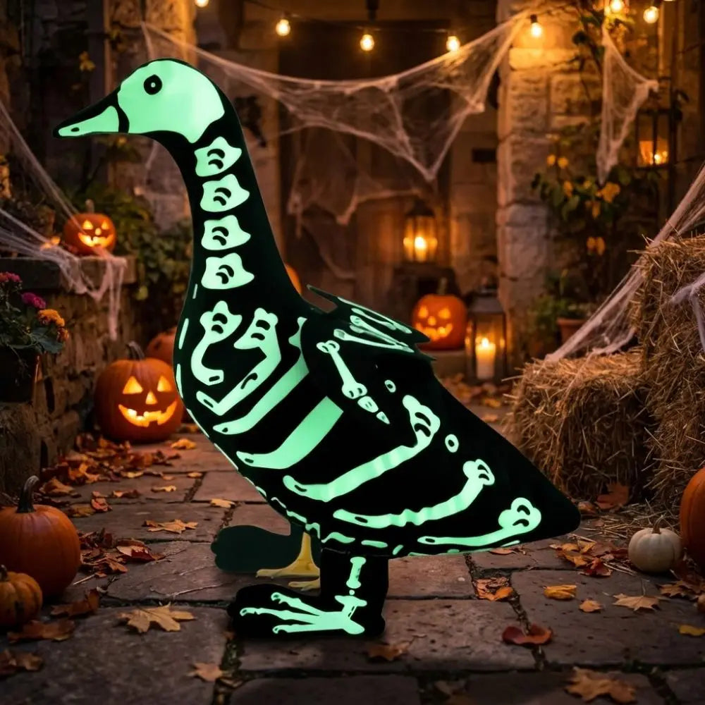 A glowing white skeleton goose lawn decor statue placed on a stone path surrounded by autumn foliage and hay bales.