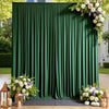 A dark green pleated fabric backdrop curtain decorated with white and purple floral arrangements for an event.