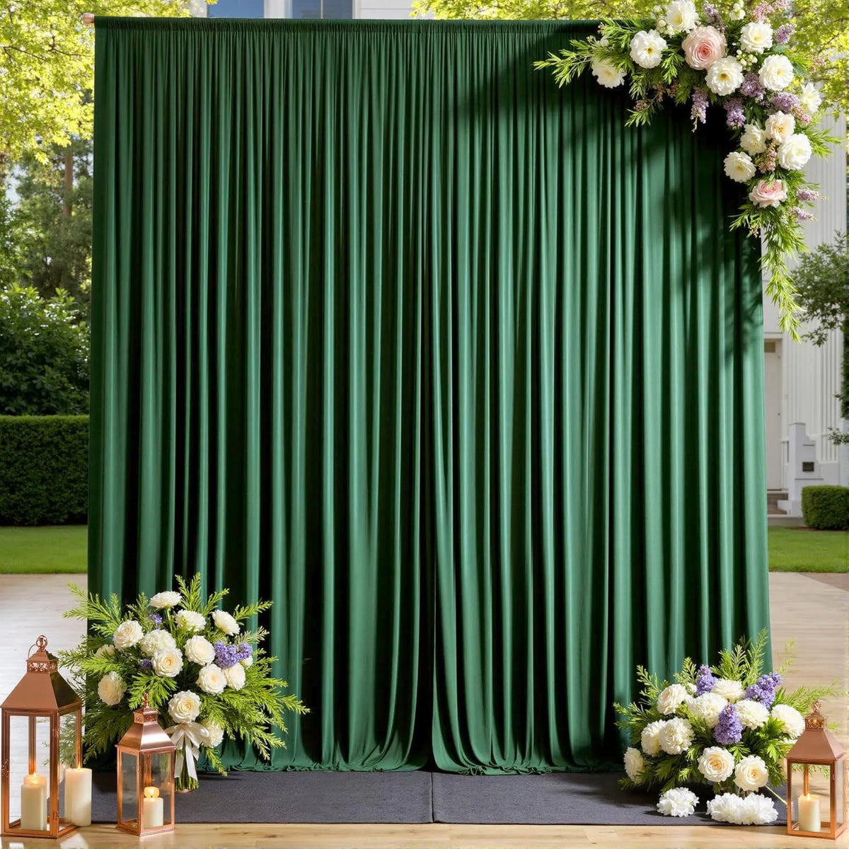 A dark green pleated fabric backdrop curtain decorated with white and purple floral arrangements for an event.