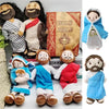 A collection of plush dolls depicting Jesus and the Virgin Mary, including a large version next to a Holy Bible.