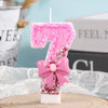 Pink glitter birthday candle shaped like the number seven with a pink bow