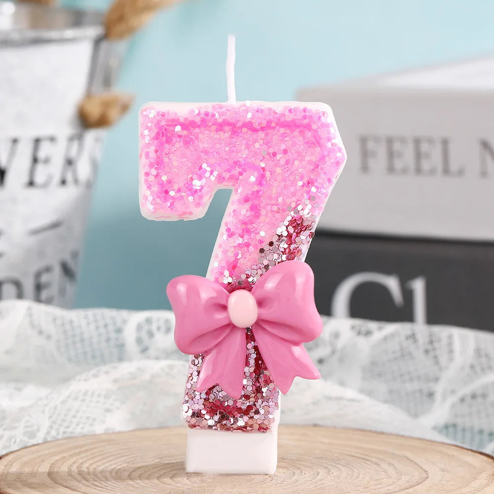 Pink glitter birthday candle shaped like the number seven with a pink bow