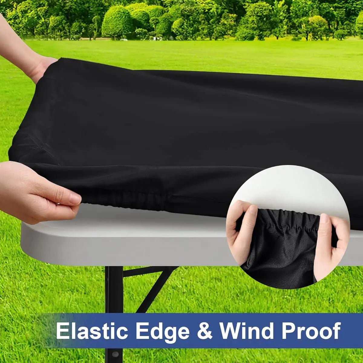 A hand is holding a black elastic edge and wind proof table cover over a white folding table outdoors.