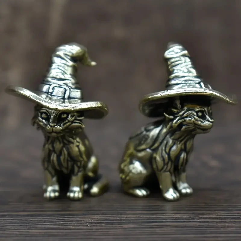 A pair of vintage brass cat statues, featuring detailed feline figures in a stylized witch hat design.