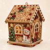 A detailed craft kit of a wooden cabin decorated with Christmas elements like snow, holly, and festive lights.