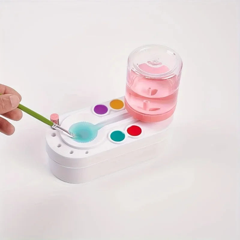 A white self-cleaning watercolor brush rinser with a pink jar and colored liquid inserts is being held by a hand.