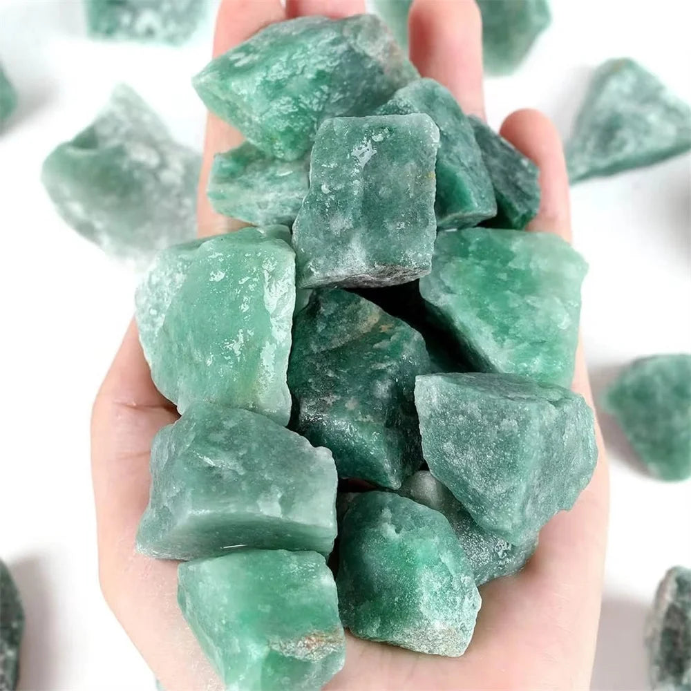 A hand holds a cluster of raw green aventurine crystal stones.