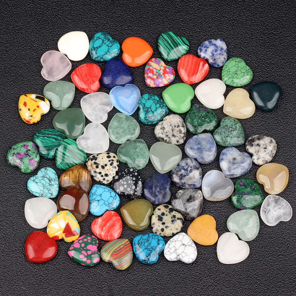 A collection of heart-shaped amethyst crystal stones in various shades of green, pink, blue, and yellow scattered on a dark s