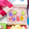 A box of silicone molds featuring festive Christmas shapes like gingerbread men and stars, with pink and green ribbon visible