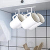 Étagère pour essuyer des tasses sous un meuble blanc avec plusieurs tasses suspendues à une barre métallique sur un mur carre