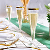 A set of glitter disposable champagne flutes displayed on a white table with green fabric and gold accents.