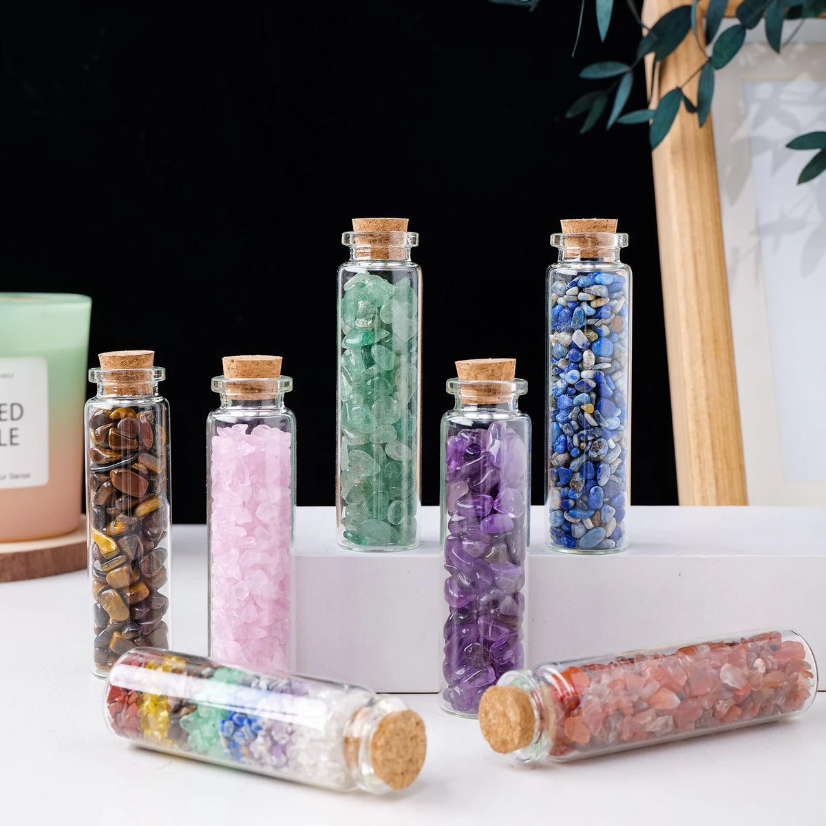 A collection of natural crystal healing drifting bottles in various colors and sizes displayed on a white surface.