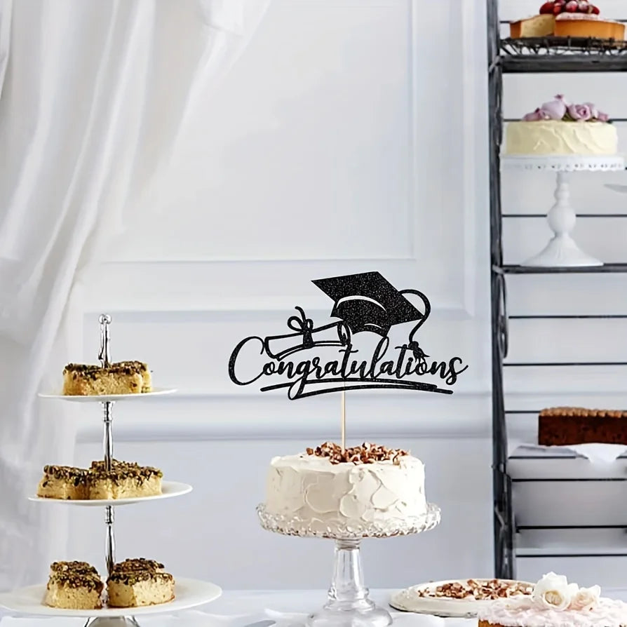 A tiered white cake with black graduation topper and decorative elements on a silver stand.