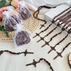 A collection of wooden rosary pendant necklaces and bags of beads displayed on a light surface.