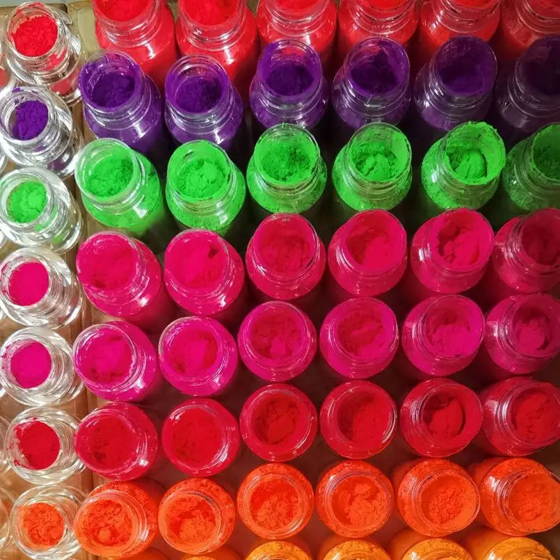 A collection of 13 vivid neon fluorescent pigment powders in various shades of pink, green, purple, and orange.