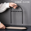 A hand is placing a leather key holder onto a black wrought iron desk organizer rack.