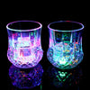 A pair of iridescent LED glow party cups reflecting light on a dark surface.