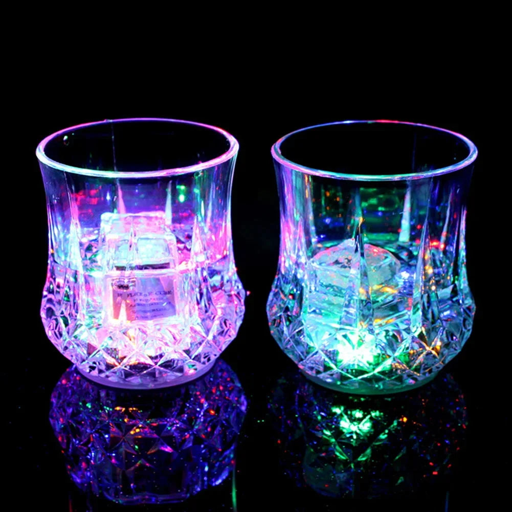 A pair of iridescent LED glow party cups reflecting light on a dark surface.