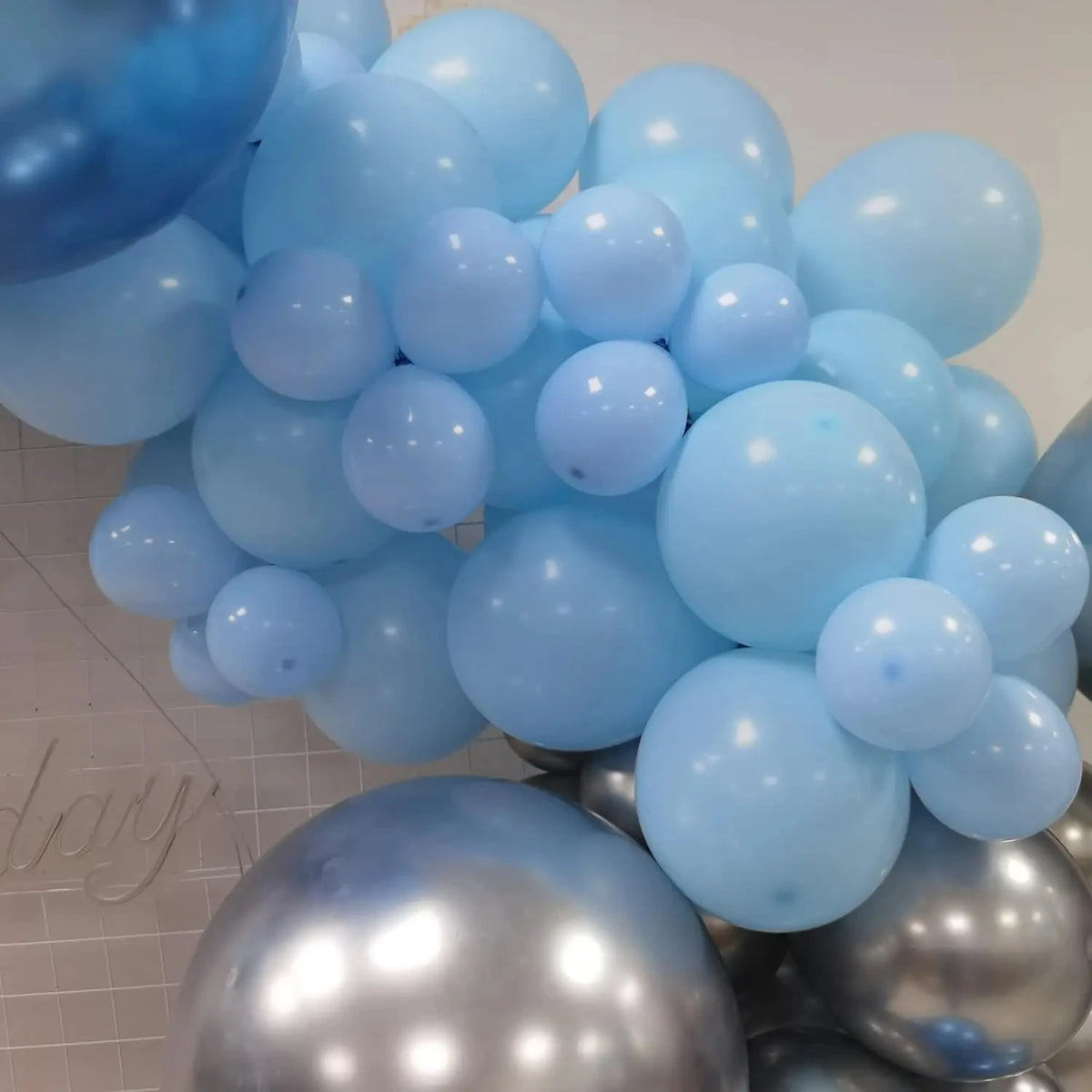 A cluster of light blue and silver balloons forming a decorative arch or grouping for party use.