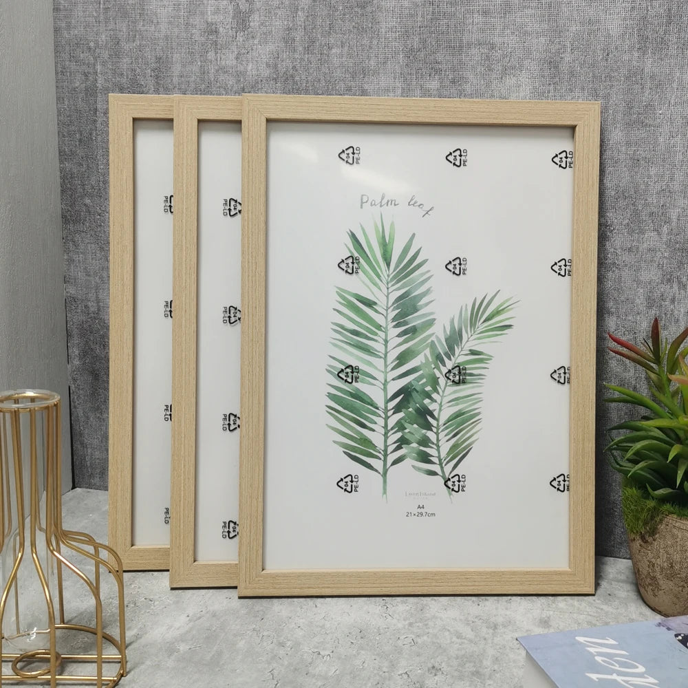 A set of three wooden photo frames with glass fronts and a botanical print for wall decor.