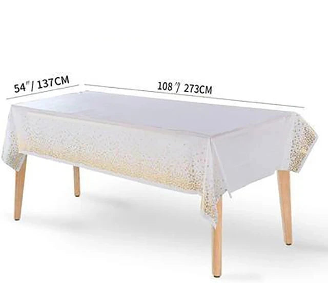 A white rectangular table draped with a sheer white cloth and gold polka dots, shown in a studio setting.