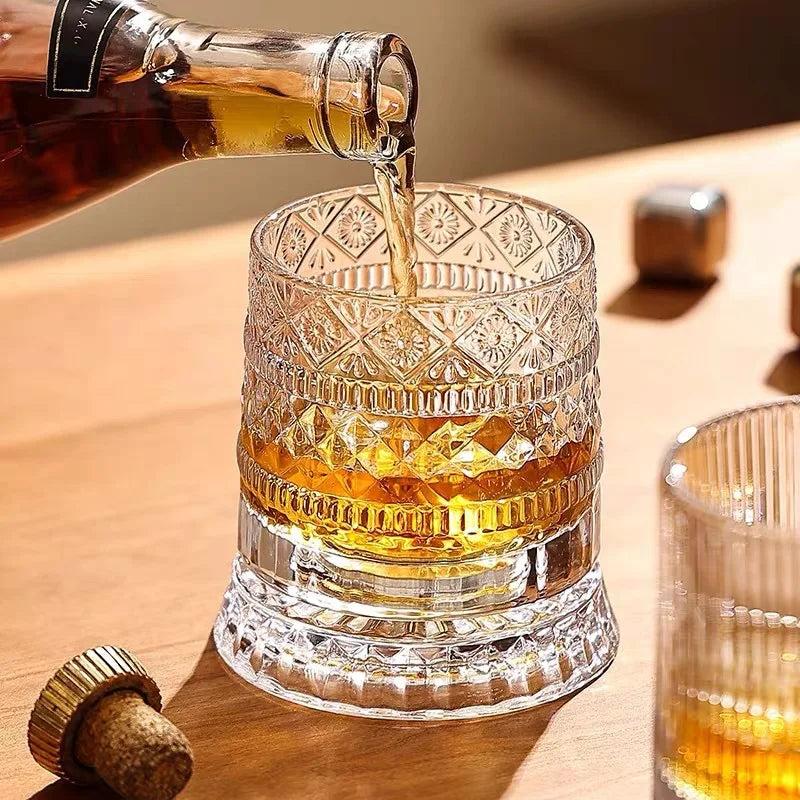 A close-up shot of a rotating crystal whiskey glass filled with amber liquid, being poured from a bottle.