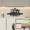 A black metal wall sign featuring kitchen utensils like whisks, spatulas, and forks, mounted on a light wood background.