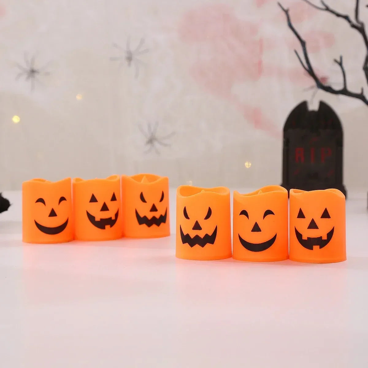 A row of bright orange flameless LED candles shaped like jack-o'-lanterns on a white surface.