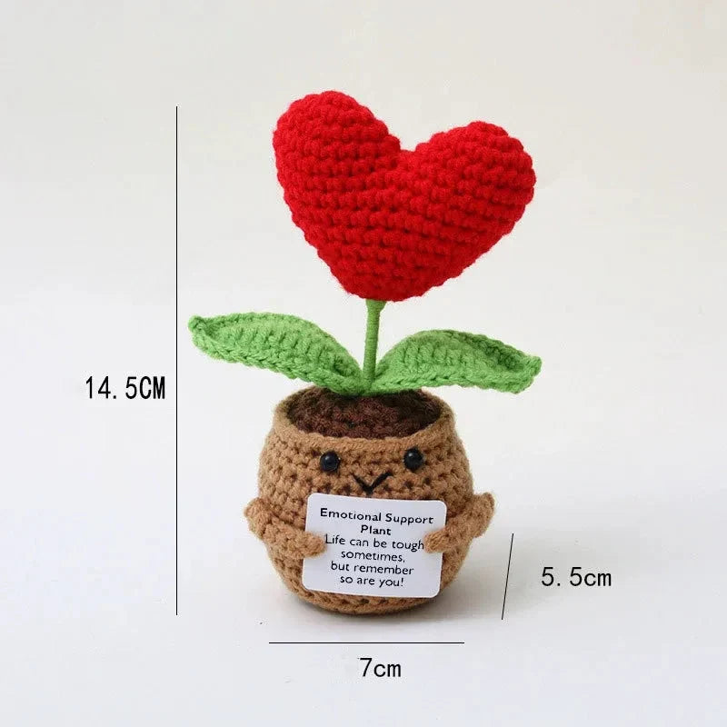 Handmade crochet plant decoration featuring a red heart flower growing from a brown potato with an inspirational card.