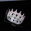 A silver crystal rhinestone crown ring with pink gemstones shown against a black background.