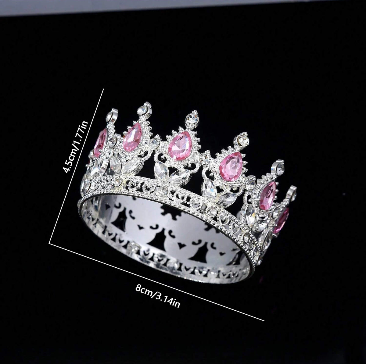 A silver crystal rhinestone crown ring with pink gemstones shown against a black background.