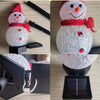 A close-up view of a solar powered outdoor Christmas snowman light with a red scarf and glowing eyes.