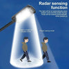 A solar-powered motion sensor LED security light shining a bright beam onto people entering and exiting.